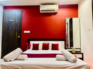 a bedroom with a red wall and a bed with red pillows at 7 Seasons Palm Suite with Sky Orbit, Balcony, Swimming pool, WIFI, Playground in Rajkot