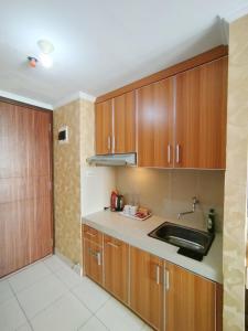 a kitchen with wooden cabinets and a sink at Disewakan Studio Fully Furnished Metropolitan Park Apartement - Bekasi in Telukpucung +17 photos