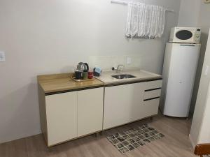 a small kitchen with a sink and a refrigerator at Pousada Le Sorelle apt03 in Rosário do Sul