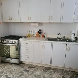 a kitchen with white cabinets and a sink and a stove at Condominio Galeón in Acapulco