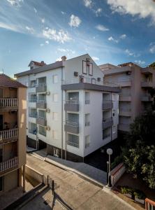 an apartment building with balconies in a parking lot at Apartmani Barović Bečići in Becici