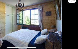 ein Schlafzimmer mit einem Bett mit Kissen und einem Fenster in der Unterkunft Grand chalet de charme cosy, sauna & vue de rêve in Ban-sur-Meurthe-Clefcy