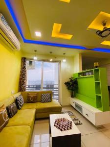 a living room with a couch and a tv at 7 Seasons Palm Suite with Sky Orbit, Balcony, Swimming pool, WIFI, Playground in Rajkot