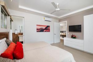 a white bedroom with a bed and a flat screen tv at Exclusive Villa in Mar Vista Community in Playa Flamingo