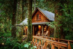a log cabin in the woods with a wooden bridge at Barlow Haus in Mount Hood Village