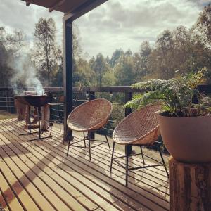 una terraza con tres sillas y una parrilla y una parrilla en Colico Lodge - tinaja -terraza, en Catrico 4 fotos más