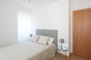a white bedroom with a bed with two pillows at Terraço da Vila in Ponte de Lima