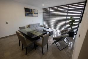 a dining room with a table and chairs and a couch at Departamentos Amaneceres Zacatlán in Zacatlán