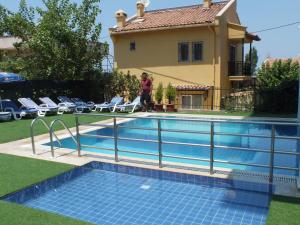 a man walking by a swimming pool in front of a house at Blue Sea Hotel & Spa in Kuşadası