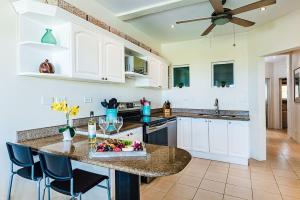a kitchen with white cabinets and a table with a bowl of fruit at Beachfront Hideaway with Pool & Ocean Views in Playa Flamingo