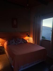 una camera da letto con un letto e una grande finestra di Aconchego do Pôr do Sol Sebollas a Inconfidência