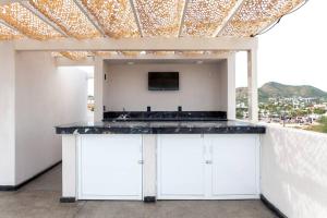 a kitchen with white cabinets and a tv on a wall at Close to Beach Nice Suite in Cabo's Downtown - 5 in Cabo San Lucas