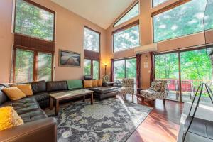 a living room with a leather couch and large windows at Charming Lakefront Getaway with Hot Tub & Game Room Perfect for Families! in East Stroudsburg