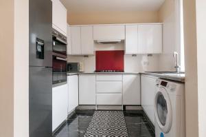 a kitchen with white cabinets and a washing machine at 2 Bed Property, sleeps 5, free parking, near city centre in Edinburgh