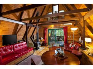 una sala de estar con sofás rojos y techo de madera. en The Mouses House Rainforest Retreat, en Springbrook