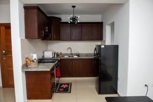 a kitchen with wooden cabinets and a black refrigerator at Luxury Aparment Bonao in Bonao