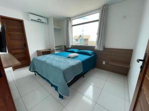 ein Schlafzimmer mit einem blauen Bett und einem Fenster in der Unterkunft Chalé Paraíso, Chaleville Maramar - Conforto, segurança, internet e Jacuzzi Vista mar in Luis Correia