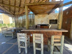 eine Bar im Freien mit Holzhockern und Tischen und Stühlen in der Unterkunft Chalé Paraíso, Chaleville Maramar - Conforto, segurança, internet e Jacuzzi Vista mar in Luis Correia