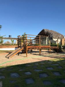 ein Spielplatz mit Holzbänken und Strohdach in der Unterkunft Chalé Paraíso, Chaleville Maramar - Conforto, segurança, internet e Jacuzzi Vista mar in Luis Correia