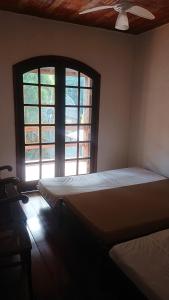 two beds in a room with two windows at Casa Helena Barequeçaba in São Sebastião