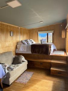 a bedroom with a bed and a couch and a window at Cabañas Sierra Dorotea in Puerto Natales