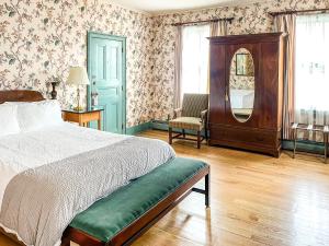 a bedroom with a bed and a mirror and a chair at The Inn at Montpelier in Montpelier