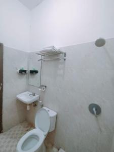 a white bathroom with a toilet and a sink at Djembank Hotel & Restaurant in Tjakranegara