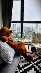 a teddy bear sitting on a couch in front of a window at Spectacular city view Near Georgetown 9 pax in Jelutong