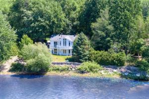 an aerial view of a white house with trees and water at ChaletBlanc in Rigaud