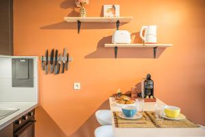 a kitchen with an orange wall with shelves at Ti Kaz Oreo - Cosy Plage & confort - Wiskeys in Saint-Gilles les Bains +27 photos