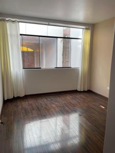 Cette chambre vide dispose d'une grande fenêtre et de parquet. dans l'établissement Dreaming wasi Standar, à Puno