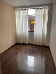 une pièce vide avec des rideaux blancs et un parquet dans l'établissement Dreaming wasi Standar, à Puno