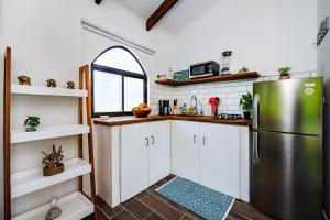 a kitchen with white cabinets and a stainless steel refrigerator at Couples Tropical Getaway with Pool, Playa Potrero in Potrero