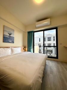una camera da letto con un letto grande e una grande finestra di 安平包棟Villa - 燈塔 a Tainan