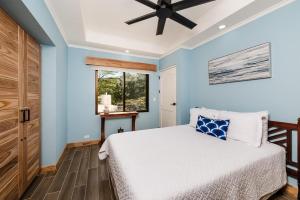 a blue bedroom with a bed and a ceiling fan at Wake Up to Ocean Views, Pool, Walk to Sandy Beach in Tamarindo
