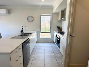 cocina con encimeras blancas, fregadero y ventana en Coastal Oasis - 10 mins to Torquay, 10 mins to Geelong !, en Mount Duneed