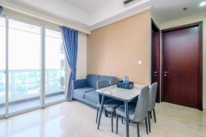 Una sala de estar con un sofá azul y una mesa y sillas. en Modern Look and Comfy 2BR at Menteng Park Apartment By Travelio, en Yakarta