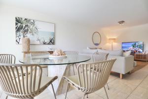a living room with a table and chairs and a couch at Chic 2 bdrm Poolside Apartment in Noosa Heads