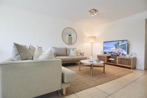 a living room with a couch and a tv at Chic 2 bdrm Poolside Apartment in Noosa Heads