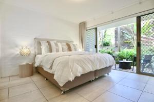 a bedroom with a bed and a large window at Chic 2 bdrm Poolside Apartment in Noosa Heads