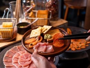 a person holding a plate of food on a table at Glamday Style Okinawa Yomitan Hotel & Resort in Yomitan