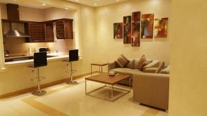 a living room with a couch and a table and a kitchen at Mandarin Alshamal Hotel Apartments in Riyadh