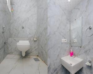 a white bathroom with a toilet and a sink at Hotel Golden Sands Inn Aslpha in Mumbai