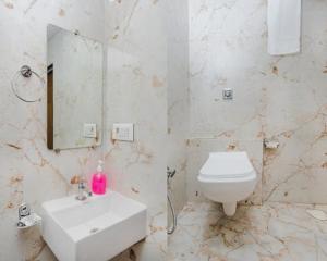 a bathroom with a sink and a toilet and a mirror at Hotel Golden Sands Inn Aslpha in Mumbai