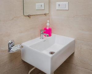 a bathroom sink with a pink soap bottle on it at Hotel Golden Sands Inn Aslpha in Mumbai