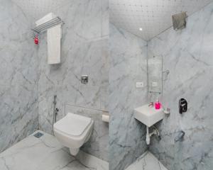 a white bathroom with a toilet and a sink at Hotel Golden Sands Inn Aslpha in Mumbai