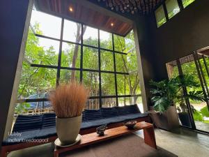 a room with a large window with a bench and plants at Inchantreedoopool in Kanchanaburi City