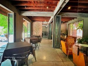 a restaurant with tables and chairs and windows at Inchantreedoopool in Kanchanaburi City