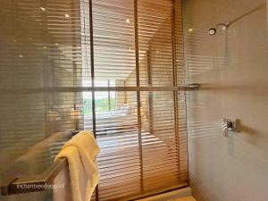 a bathroom with a shower and a window with towels at Inchantreedoopool in Kanchanaburi City