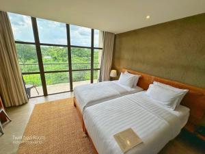 a bedroom with two beds and a large window at Inchantreedoopool in Kanchanaburi City